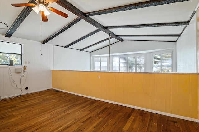 spare room with hardwood / wood-style flooring, plenty of natural light, lofted ceiling with beams, and wood walls