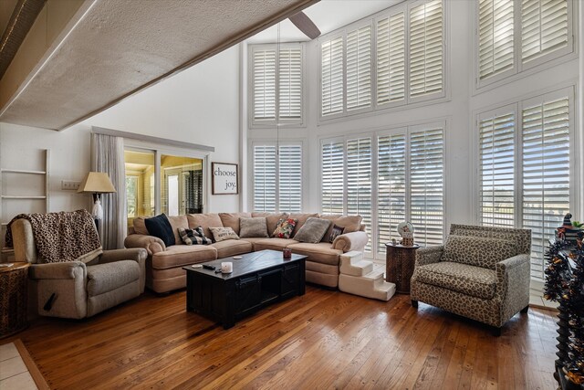 living room featuring a textured ceiling, dark hardwood / wood-style flooring, and a high ceiling