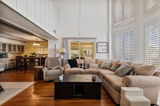 living room with a towering ceiling, dark hardwood / wood-style flooring, and an inviting chandelier