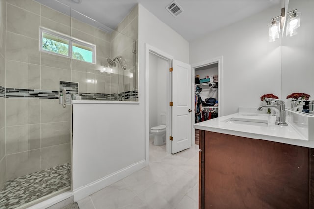 bathroom featuring vanity, toilet, and tiled shower