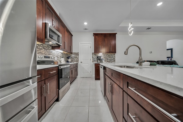 kitchen featuring hanging light fixtures, stainless steel appliances, sink, light tile patterned flooring, and tasteful backsplash