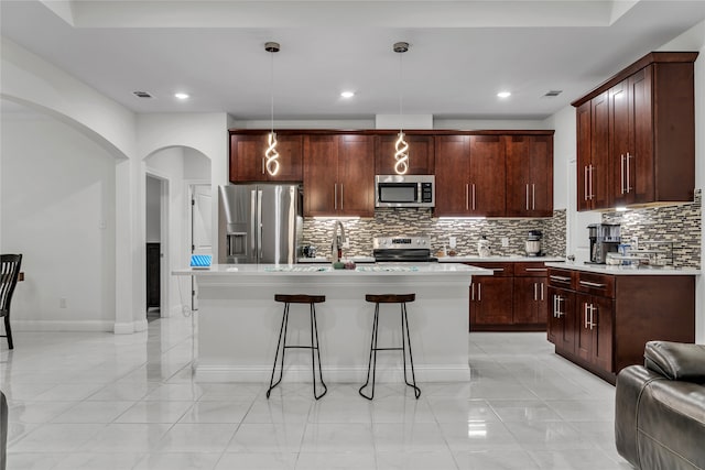 kitchen with a kitchen island, decorative backsplash, decorative light fixtures, and stainless steel appliances