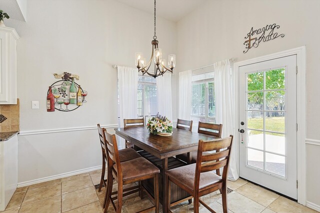 dining room featuring a towering ceiling, light tile patterned flooring, and an inviting chandelier