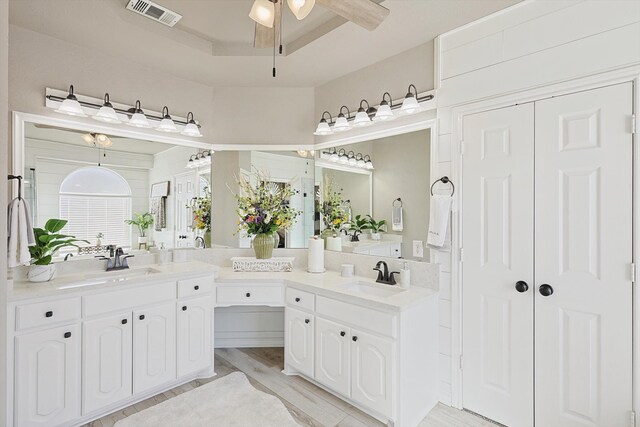 bathroom with vanity, hardwood / wood-style flooring, a tray ceiling, and ceiling fan