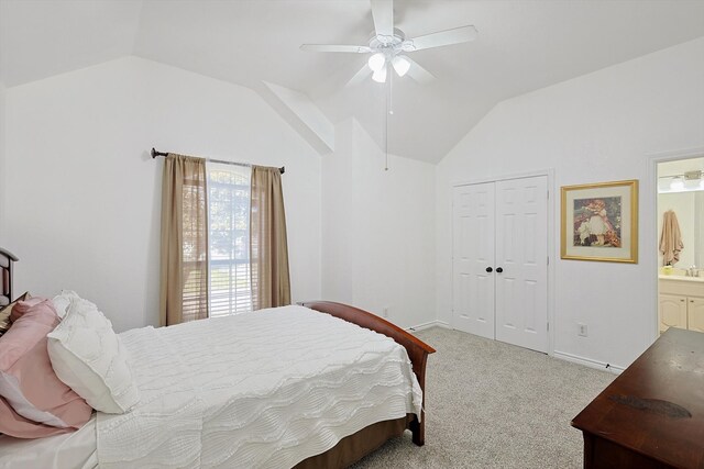 carpeted bedroom with a closet, ensuite bathroom, vaulted ceiling, and ceiling fan