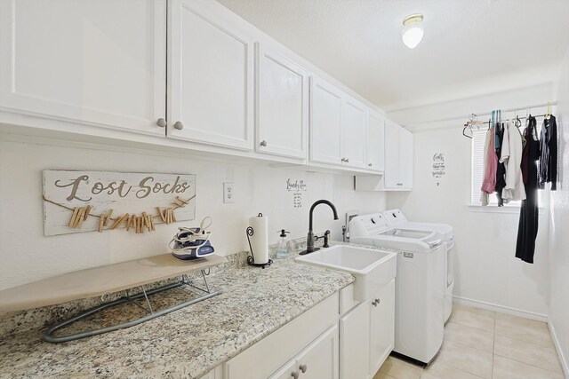 washroom with sink, washing machine and clothes dryer, light tile patterned floors, and cabinets