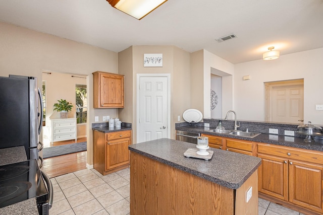 kitchen featuring sink, a center island, light tile patterned floors, kitchen peninsula, and stainless steel appliances