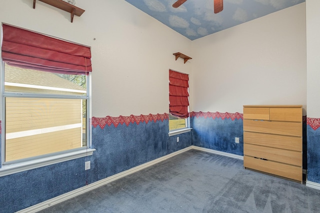 unfurnished bedroom featuring vaulted ceiling, dark carpet, and ceiling fan