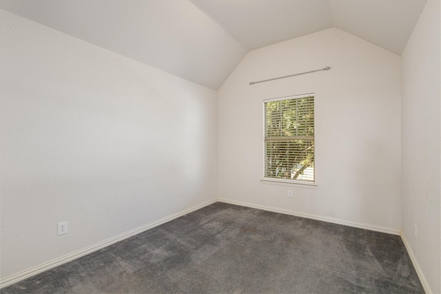 empty room featuring dark colored carpet and vaulted ceiling