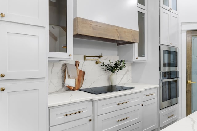 kitchen featuring light stone countertops, appliances with stainless steel finishes, white cabinetry, and backsplash