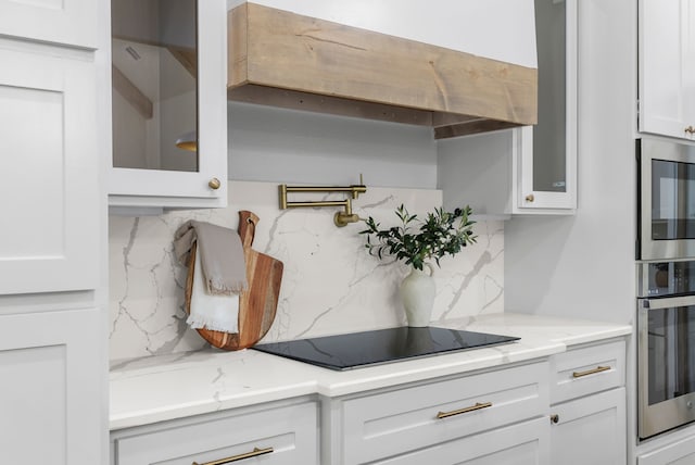 kitchen featuring appliances with stainless steel finishes, white cabinetry, tasteful backsplash, and light stone counters