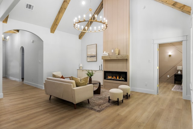 living room featuring light hardwood / wood-style flooring, a tiled fireplace, beamed ceiling, and high vaulted ceiling