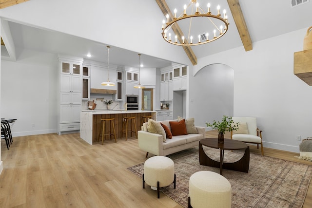 living room featuring sink, lofted ceiling with beams, and light wood-type flooring