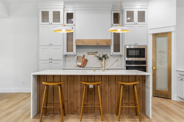 kitchen with appliances with stainless steel finishes, decorative light fixtures, and light wood-type flooring