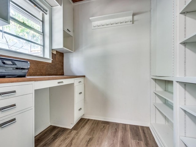 interior space featuring white cabinetry, built in desk, and dark wood-type flooring