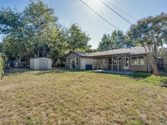 rear view of property with a lawn, a storage shed, and a patio