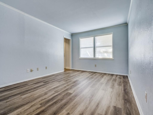 spare room featuring wood-type flooring and ornamental molding