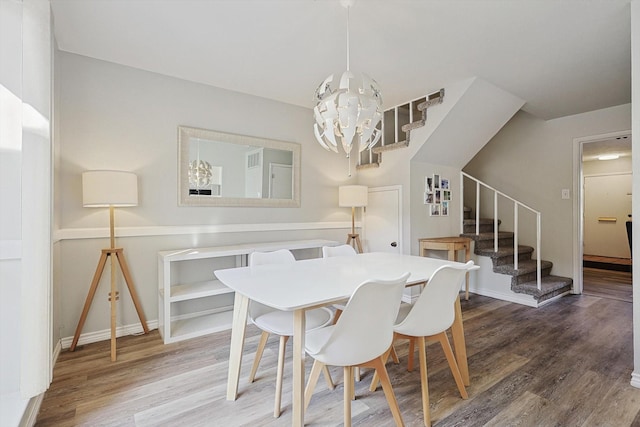 dining area with wood-type flooring and an inviting chandelier