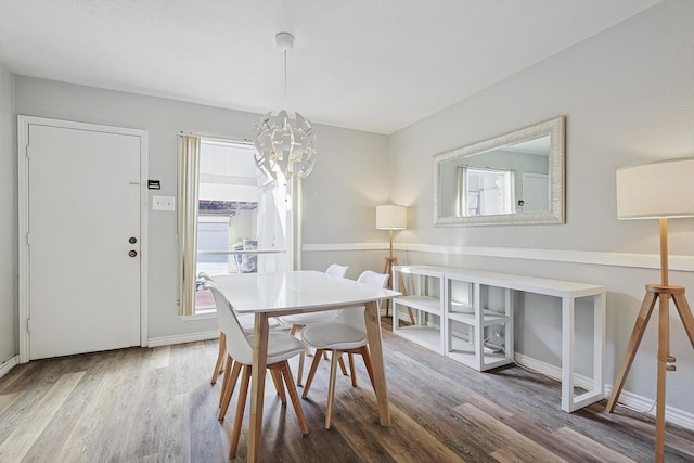 dining space with wood-type flooring, a wealth of natural light, and an inviting chandelier