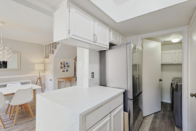 kitchen featuring hanging light fixtures, stainless steel refrigerator, dark hardwood / wood-style flooring, independent washer and dryer, and white cabinets