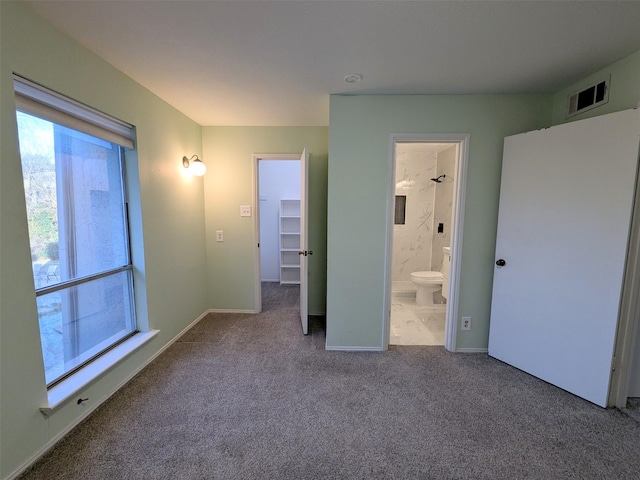 unfurnished bedroom with ensuite bath, carpet flooring, and a spacious closet