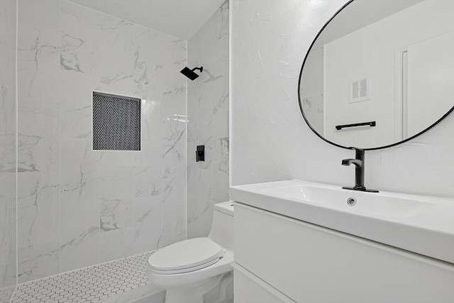 bathroom with vanity, toilet, and tiled shower