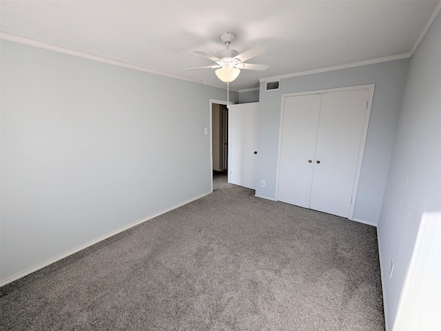 unfurnished bedroom featuring dark colored carpet, a closet, ceiling fan, and crown molding