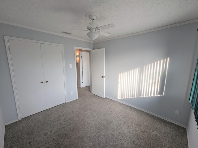 unfurnished bedroom with carpet flooring, ceiling fan, a textured ceiling, a closet, and ornamental molding