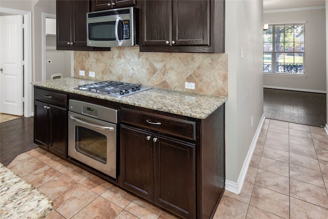 kitchen featuring appliances with stainless steel finishes, ornamental molding, light stone countertops, and light wood-type flooring