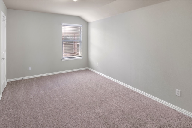 spare room with carpet flooring and vaulted ceiling