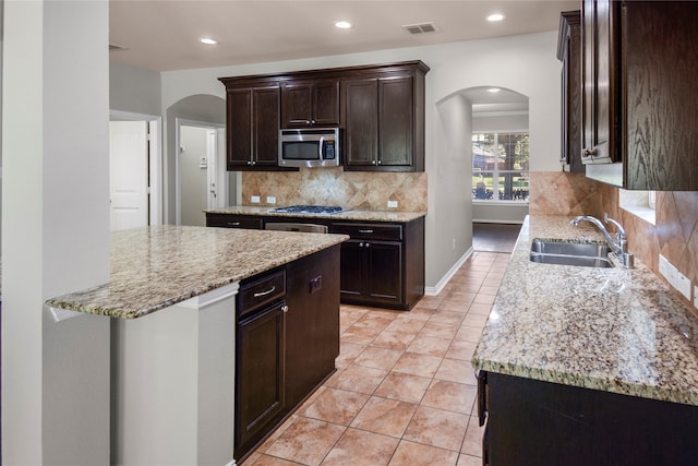 kitchen featuring tasteful backsplash, sink, stainless steel appliances, light stone counters, and light tile patterned floors