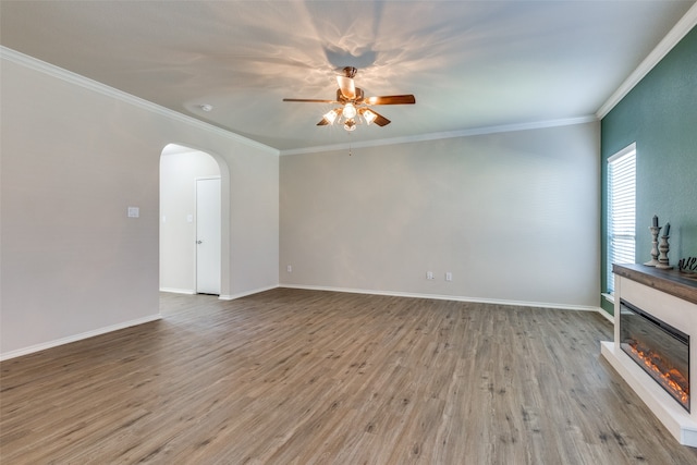 unfurnished living room with ceiling fan, ornamental molding, and light wood-type flooring