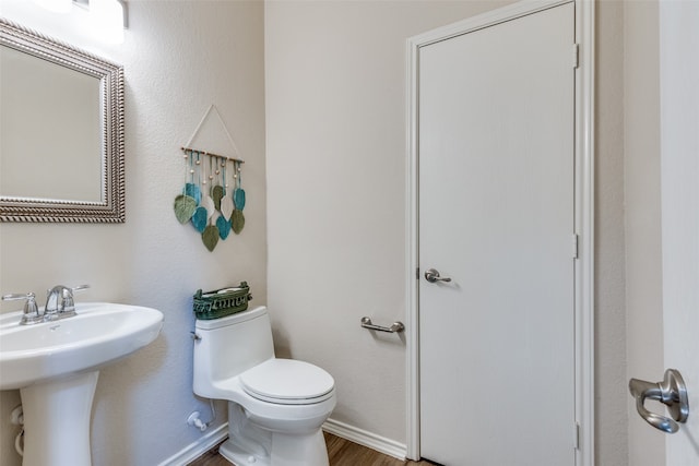 bathroom with toilet, hardwood / wood-style floors, and sink