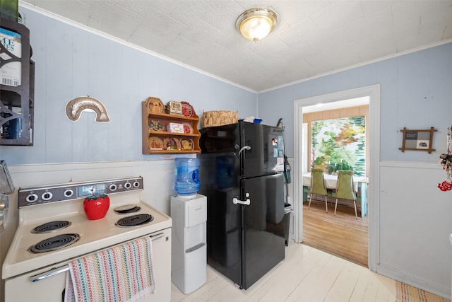 kitchen with crown molding, electric range oven, light wood-type flooring, and black fridge