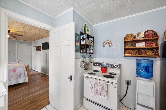 kitchen with electric range, ceiling fan, wood-type flooring, ornamental molding, and wooden walls