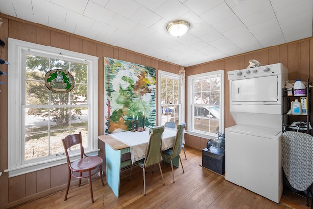 dining room with hardwood / wood-style floors, a healthy amount of sunlight, and stacked washer and dryer