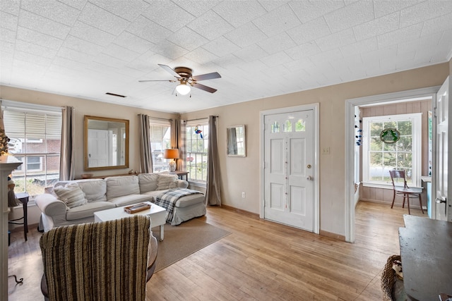 living room with a wealth of natural light, light hardwood / wood-style flooring, and ceiling fan