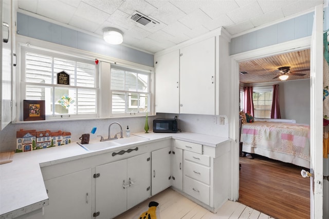 kitchen featuring light hardwood / wood-style flooring, white cabinets, a healthy amount of sunlight, and sink