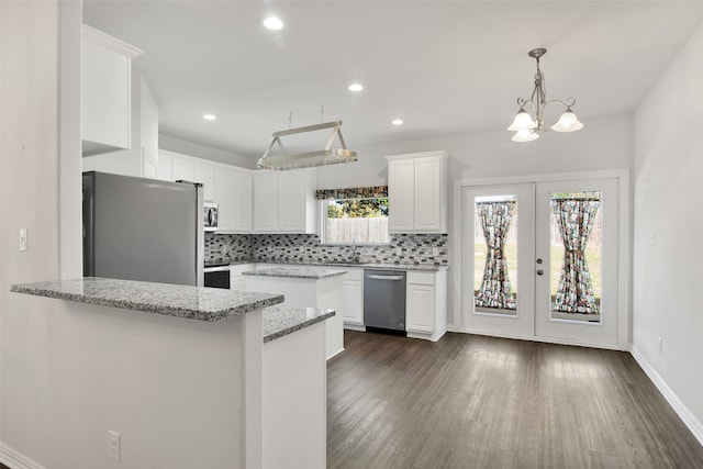 kitchen featuring light stone counters, stainless steel appliances, backsplash, and white cabinets