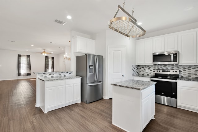 kitchen with light stone counters, wood-type flooring, a center island, stainless steel appliances, and white cabinets