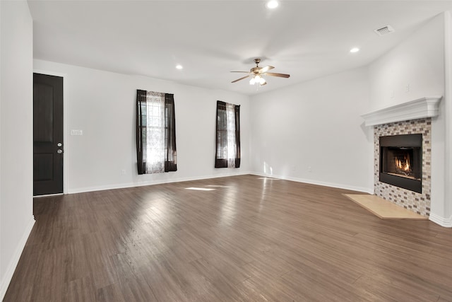 unfurnished living room featuring ceiling fan, dark wood-type flooring, and a tiled fireplace