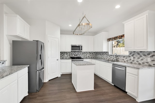 kitchen featuring sink, appliances with stainless steel finishes, a center island, light stone counters, and white cabinets