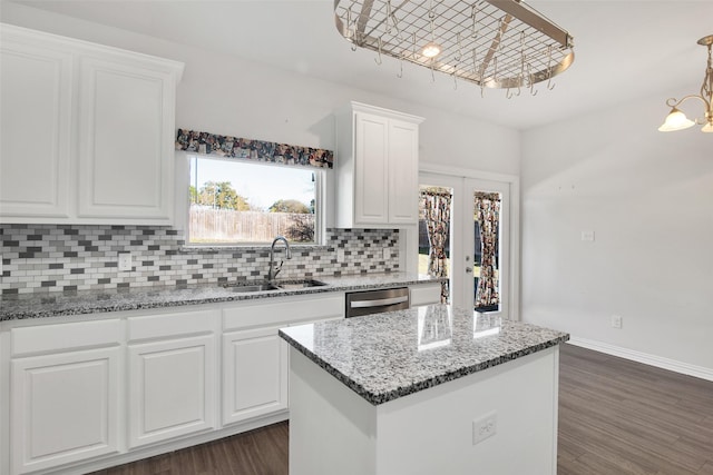 kitchen featuring a center island, sink, white cabinets, and decorative light fixtures