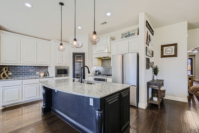 kitchen featuring light stone countertops, sink, an island with sink, appliances with stainless steel finishes, and white cabinetry