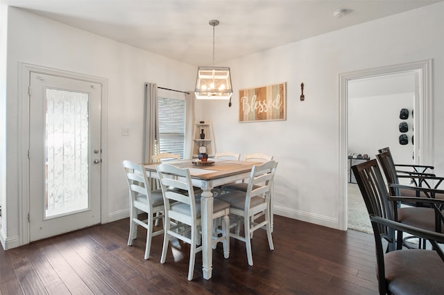 dining space with dark wood-type flooring and a notable chandelier