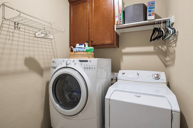 clothes washing area featuring washing machine and clothes dryer and cabinets