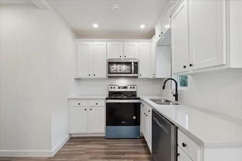 kitchen with white cabinetry, stainless steel appliances, sink, and dark hardwood / wood-style flooring