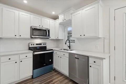 kitchen with white cabinets, stainless steel appliances, sink, and dark hardwood / wood-style floors