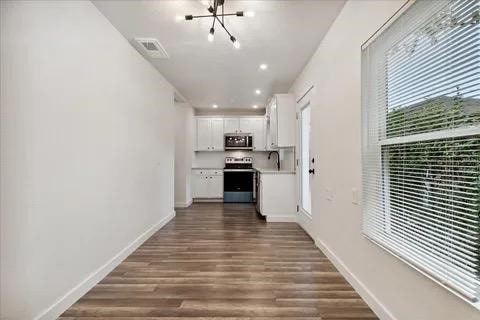 kitchen with white cabinetry, appliances with stainless steel finishes, dark hardwood / wood-style flooring, and a chandelier