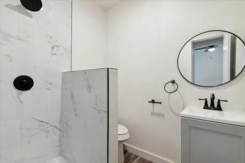 bathroom featuring vanity, tiled shower, and toilet